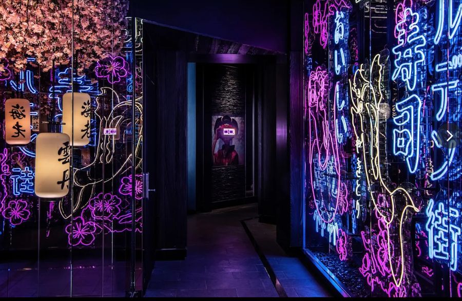 Neon-lit corridor at WAKUDA with cherry blossom and Japanese script signage